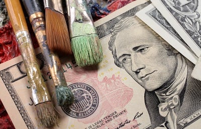 A dollar bill accompanied by used paint brushes