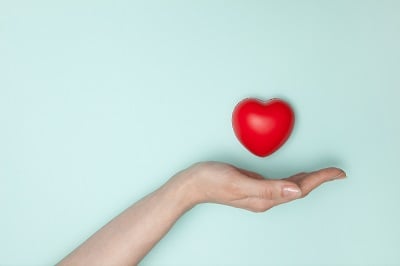 An outstretched hand holding a red heart