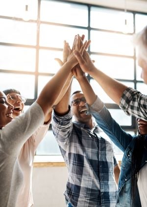 A team puts their hands together in celebration of shared success.