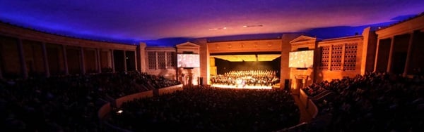 The wide modern auditorium at Toledo Alliance for the Performing Arts, viewed from the back with a large ensemble onstage, lit in blue