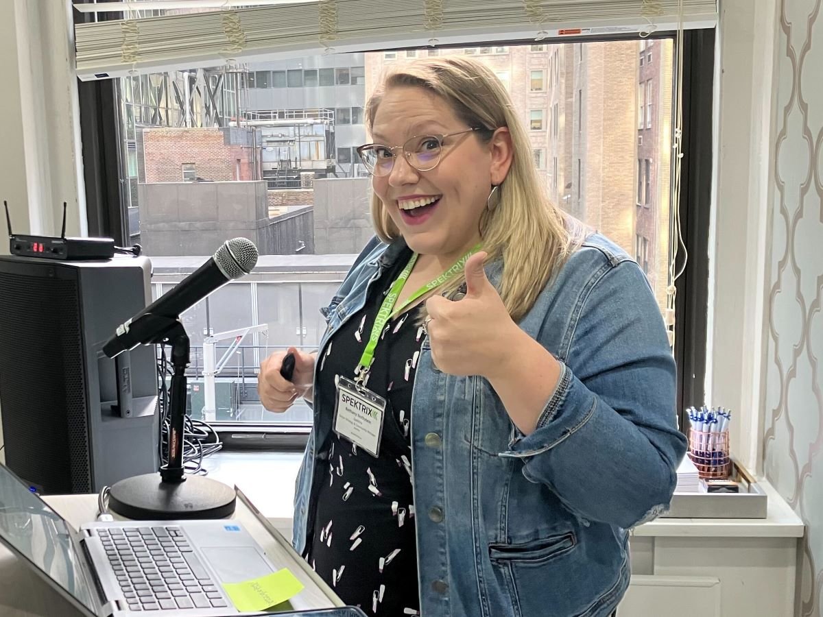 Bethany Nothstein, a blond woman in denim jacket, shows excitement with a thumbs up