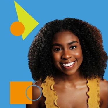 A headshot of Nickasey Freeman, a smiling black women in her early twenties with curly shoulder length black hair wearing a frilly, mustard yellow, tank top.
