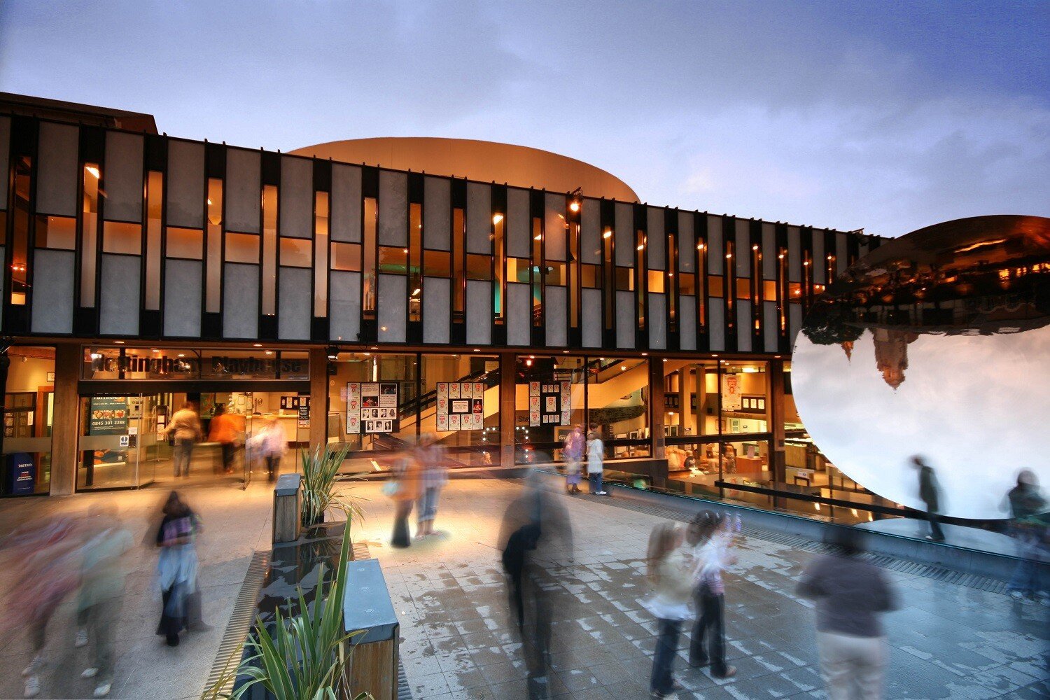 an exterior look at Nottingham Playhouse with blurred images of people on the plaza