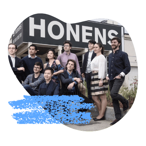 The team gather beneath a large Honens sign