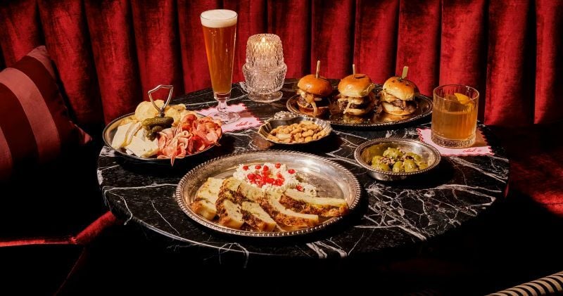 A table full of food like sliders and whipped feta at The X Speakeasy in Chicago, Illinois.