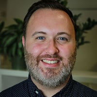 A headshot of Mark Smith, a man with brown hair and a full beard, wearing a button down shirt and smiling into the camera. A headshot of Mark Smith, a man with brown hair and a full beard, wearing a button down shirt and smiling into the camera.
