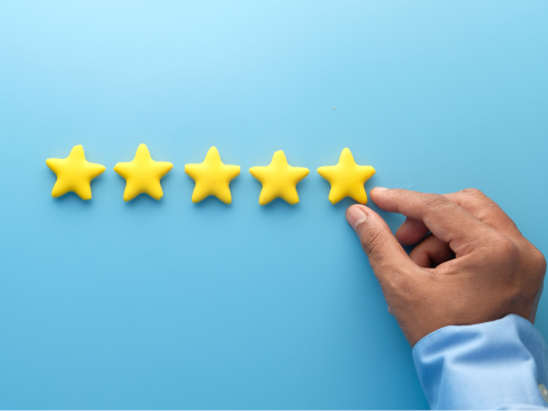 an image of a hand placing a row of five stars on a blue wall