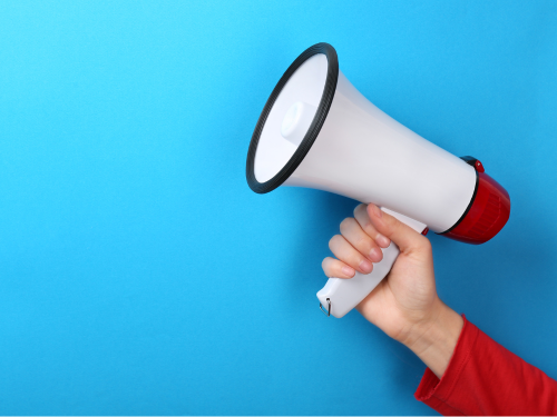an image of a hand holding a bullhorn against a bright blue background