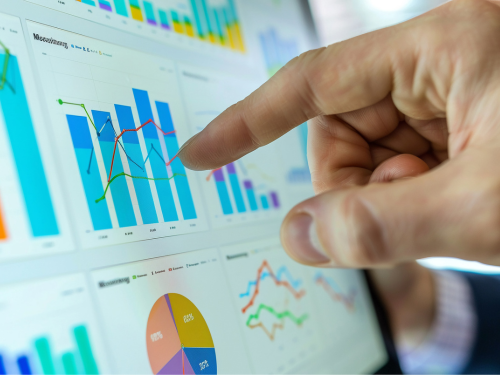 an image of a hand pointing to analytics graphs on a screen