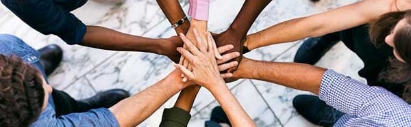 Hands joined in a circle, showing a diverse range of skin tones