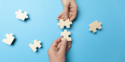 Two hands assembling a puzzle together
