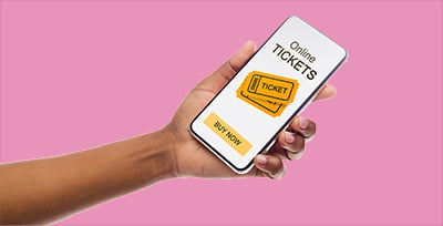 A hand holds a phone with digital tickets on the screen