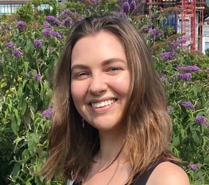 Alicia Moeller standing in front of a flower garden, smiling at the camera