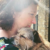 Bryony Bell is a white woman with curly hair, pictured with her dog Rita