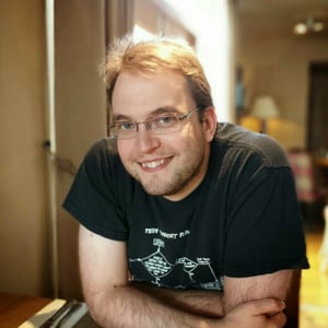 Peter Street, a white male of around 40, smiling into camera waring a dark t-shirt with a blurred background