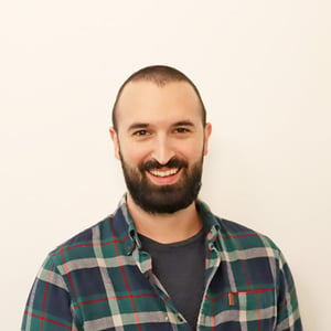 A bearded man in his early 30's, wearing a green flannel shirt, smiling and having the time of his life!