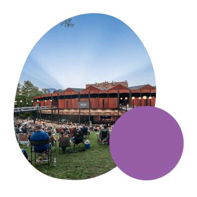 a view of the exterior of the saratoga performing arts center during a concert with audience members sitting on the lawn