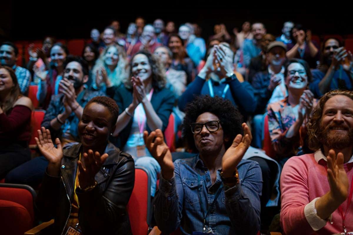 Audience in a theatre clapping and smiling