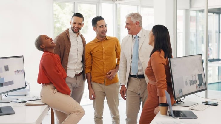 A group of arts professionals stand in a semicircle, smiling and laughing. 