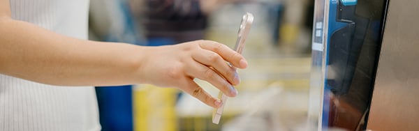 a person holding their phone to a card reader