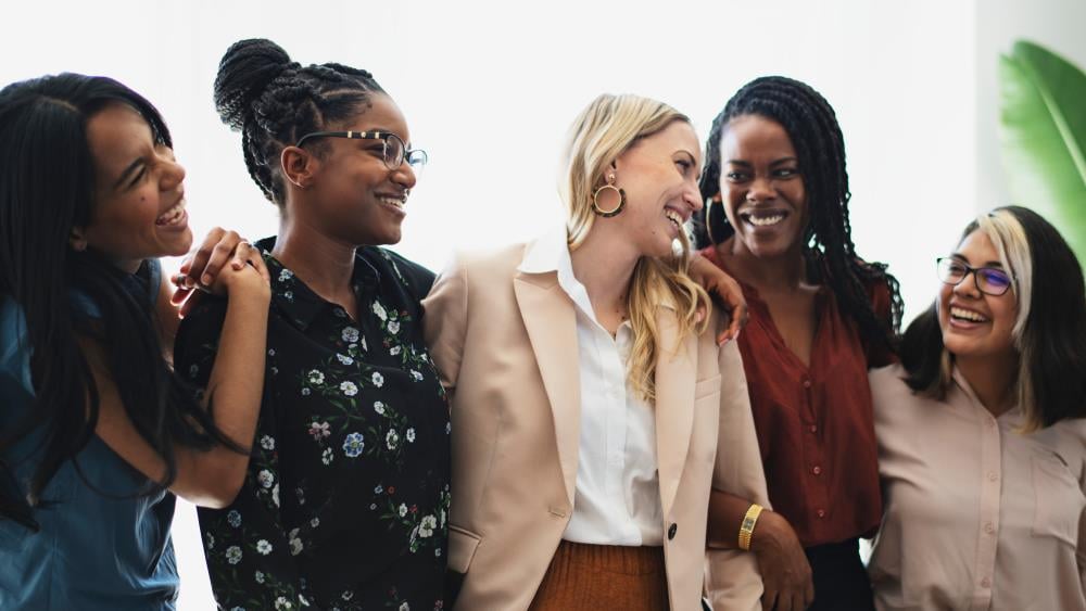 A team of arts professionals smile and laugh together as they collaborate.