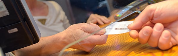 a person handing a customer a ticket through a screen