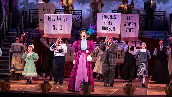 Performers in Victorian costume hold placards onstage at Waterville Creates