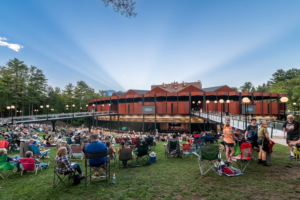 Patrons seated on folding chairs on a summer evening, awaiting an outdoor performance at Saratoga Performing Arts Center