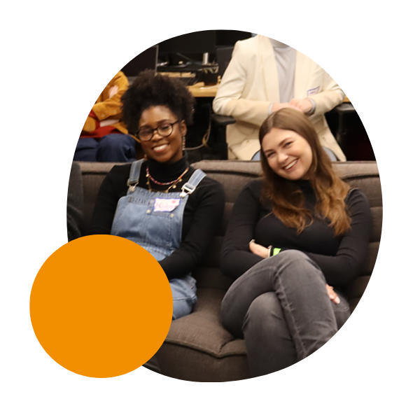 two team members sit together and smile during a together day event in nyc