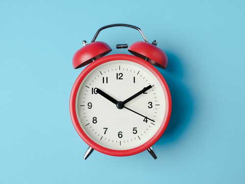 A red alarm clock on a blue background. 