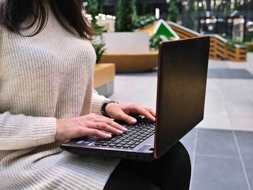 A woman working on laptop outside.