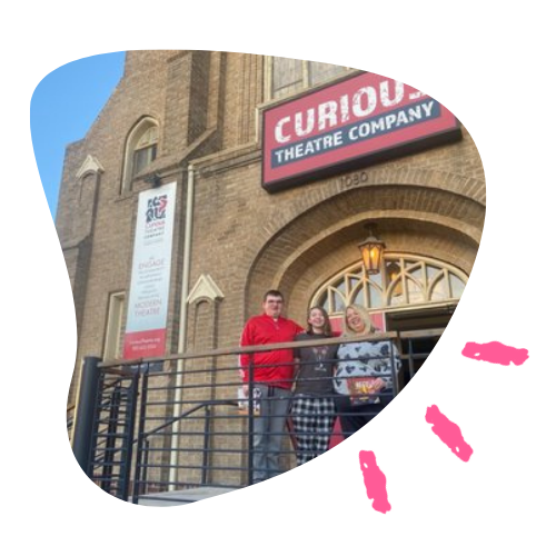 Three members of the Curious team stand on the front steps of their building, a converted church
