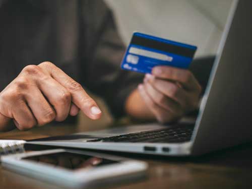 A person entering info from a credit card on a laptop.