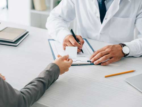 A woman handing an insurance card to a doctor.