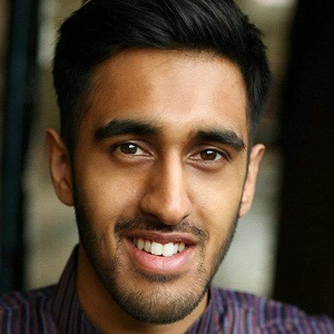 A headshot of Huzeifah Hussein.  A man with black hair, wearing a wear a traditionally indian kurta and smiling, whilst looking into camera