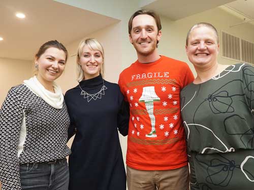 Four people standing in a row smiling. 