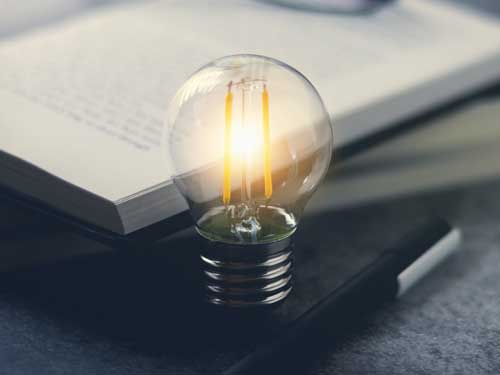 A bright light bulb leaning against a notebook.