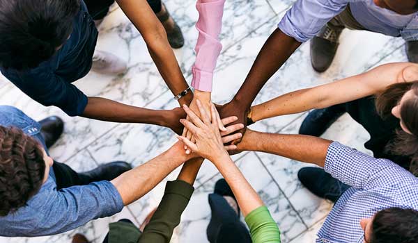 Overhead of a diverse team circled up with hands together in the middle