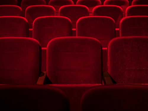 Empty rows of red theater seats.