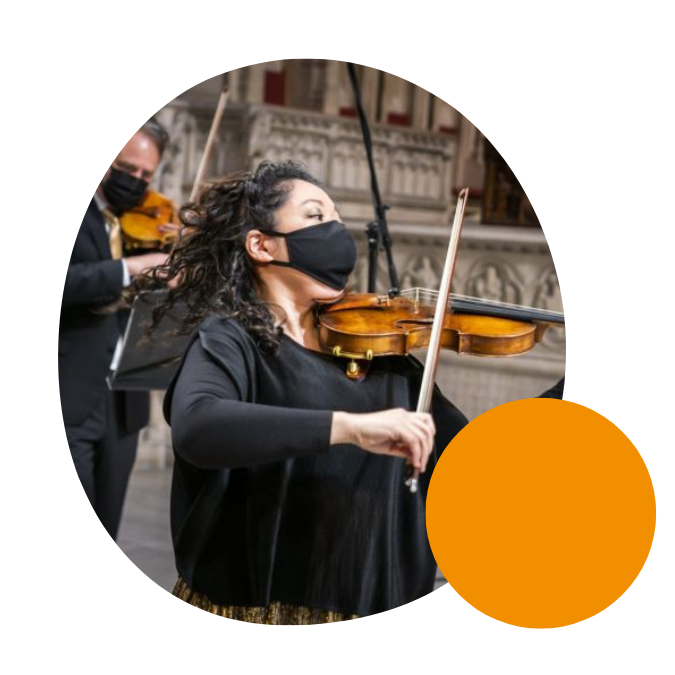 A woman playing violin in the Orpheus Chamber Orchestra