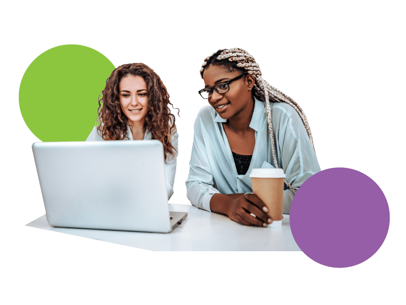 two women work together at a table with a laptop and coffee