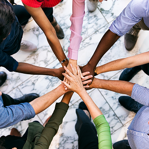 Overhead of a diverse team circled up with hands together in the middle